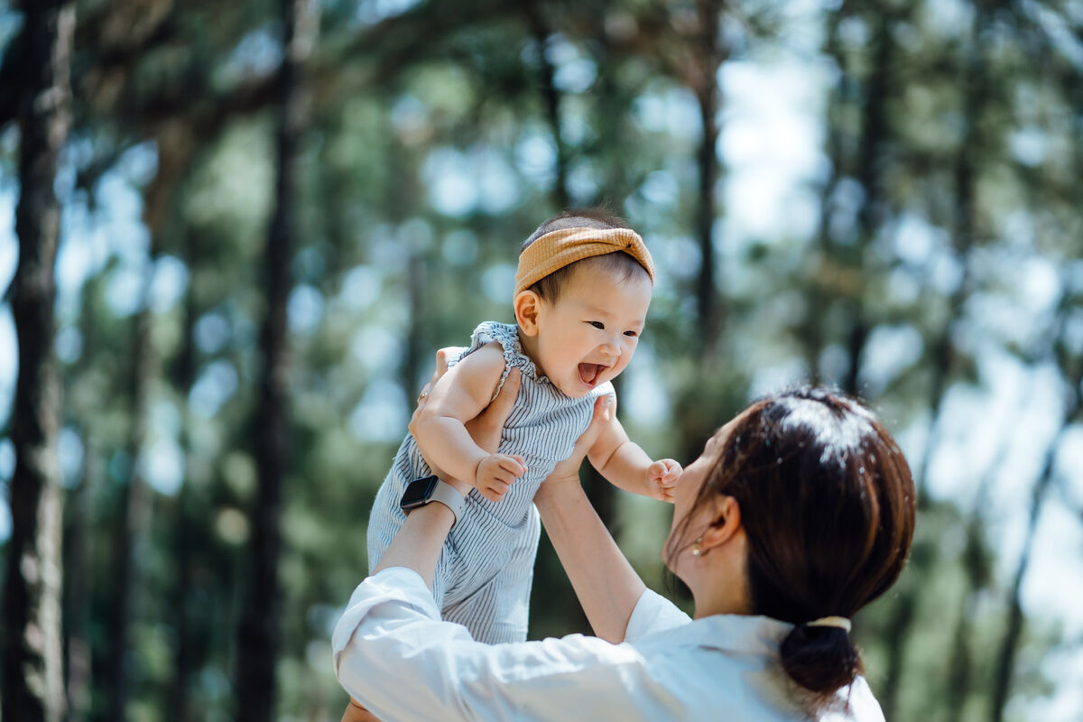 Mother joyfully playing with her baby in nature